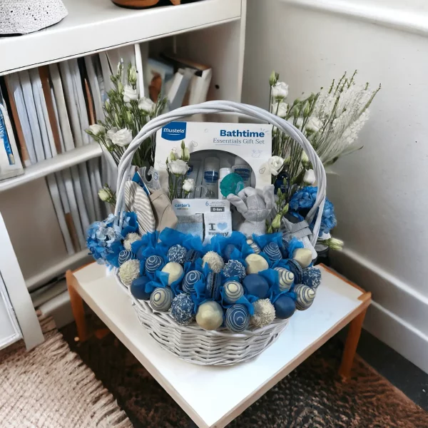 A detailed display of a baby gift basket with a variety of items for a newborn, emphasizing the included Mustella Bathtime Gift Set and a pacifier.