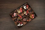 Custom-made chocolate hearts in a gift box, offering a mix of crunchy nuts, soft marshmallows, and tart strawberries, perfect for Valentine's Day or as a loving gesture.