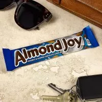 Close-up of an Almond Joy bar, revealing its coconut filling topped with whole almonds and covered in milk chocolate.