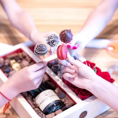Festive luxury gift box featuring fine champagne, beautiful fresh flowers, delicate macaroons, and strawberries dipped in gourmet chocolate.