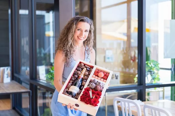 Chic gourmet gift box with luxury champagne, vibrant bouquet of flowers, sweet macaroons, and tempting chocolate-dipped strawberries.
