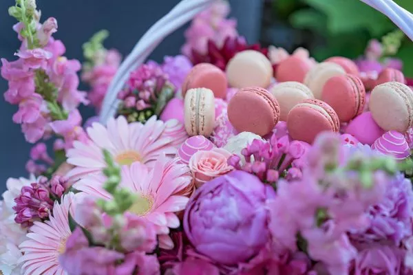 Handcrafted macarons alongside fresh flowers in a premium gift basket.