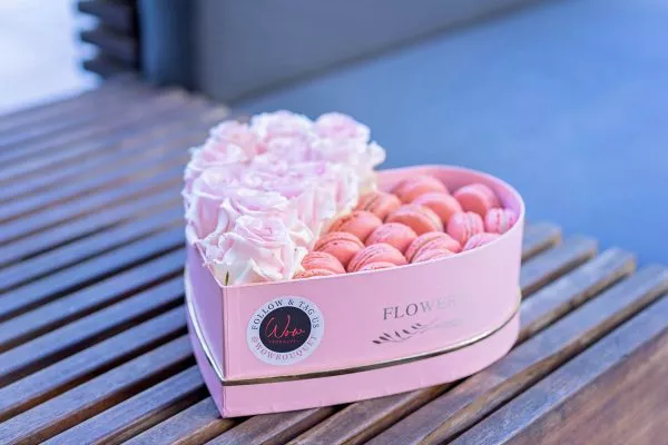 Roses and macarons arrangement in a romantic heart-shaped presentation.