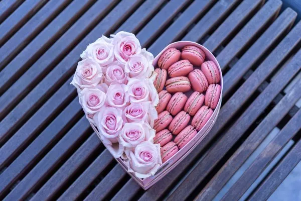 Heart-shaped box showcasing vibrant roses and gourmet macarons.