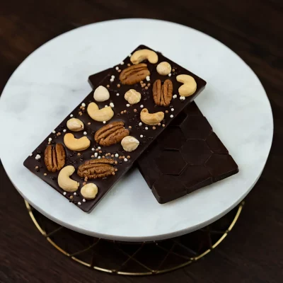 Delicious Nuts Dark Chocolate Bar featuring a rich blend of dark chocolate with whole pecans, hazelnuts, and cashews, showcasing a perfect harmony of smooth, deep chocolate and crunchy, nutty accents