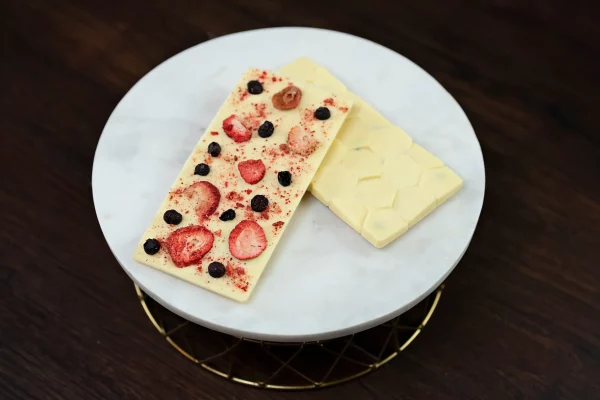 Premium white chocolate bar with vibrant freeze-dried strawberries, blueberries, and raspberries, showcasing a colorful and appetizing blend of creamy chocolate and crisp, fruity toppings.
