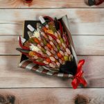 A bouquet featuring an array of smoked meats and cheese cubes, artfully skewered and arranged in a patterned container.