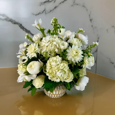 Side view of The Plaza arrangement with white flowers and lush greenery.